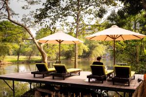 a man sitting on a dock with chairs and umbrellas at Trang An Ecolodge in Ninh Binh