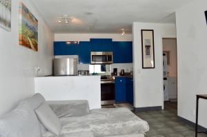 a living room with a couch and a kitchen with blue cabinets at Modern 1-Bedroom Condo in Las Vegas