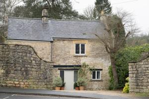 ein altes Steinhaus mit einer weißen Tür in der Unterkunft Fern Cottage Coach House in Batheaston