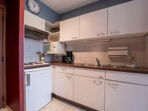 a kitchen with white cabinets and a clock on the wall at Studio Studio 502 by Interhome in Bredene +19 photos