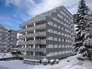 a apartment building in the snow with a tree at Apartment Sunnmatt 752 by Interhome in Engelberg
