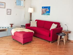 a living room with a red couch and a stool at Studio Silence Apt- H by Interhome in Wengen +28 photos