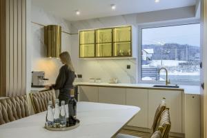 a woman standing in a kitchen next to a window at MK Premium Apartamenty in Tylicz +53 photos