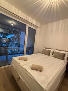 a bedroom with a large white bed with a window at Apartman Šumski Rog Bjelašnica in Bjelašnica