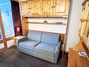 a couch in a living room with wooden cabinets at Apartment Eskival 106 by Interhome in Val Thorens