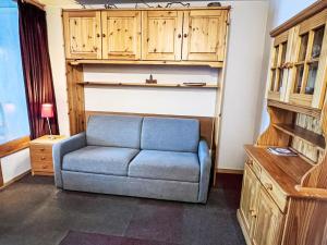 a blue couch in a living room with wooden cabinets at Apartment Eskival 106 by Interhome in Val Thorens