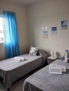 - 2 lits dans une chambre dotée de rideaux bleus dans l'établissement Apartamento Praia do Sonho- CasaMora, à Palhoça