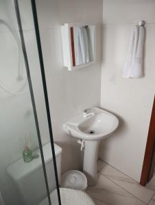 une salle de bain blanche avec un lavabo et des toilettes dans l'établissement Apartamento Praia do Sonho- CasaMora, à Palhoça