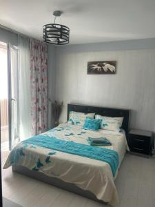 Un dormitorio con una cama con sábanas azules y una ventana. en Felicity 1, en Craiova