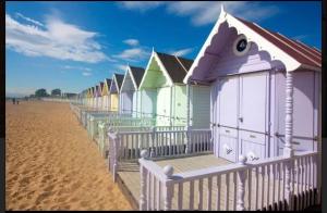 a row of colorful beach huts on the beach at Stylish Inviting 2 Bedroom Caravan with Sea View in East Mersea