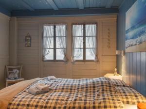 1 dormitorio con 1 cama con manta a cuadros y ventanas en Chalet Le Cabanon by Interhome, en Saint-Gingolph