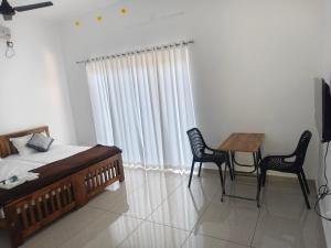 a bedroom with a bed and a table and chairs at Waves Beach Homestay in Alleppey