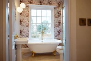 a bathroom with a tub and a sink and a window at The Manor Lodge, Repton - Luxury Derbyshire Home Sleeps 14 in Repton