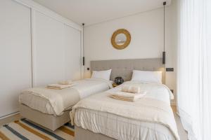 Duas camas num quarto com paredes brancas e um espelho. em Casa Evangeline, luxury villa with ocean view na Lourinhã mais 26 fotografias