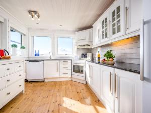 a white kitchen with white cabinets and wooden floors at Holiday Home Sjøbuvågen by Interhome in Korssund