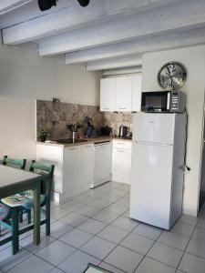 une cuisine avec des armoires blanches et un réfrigérateur blanc dans l'établissement villa les bastides de l olivier grau du roi, au Grau-du-Roi