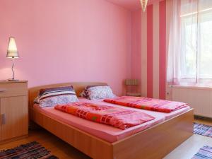 - une chambre avec des murs roses et un lit avec des draps rouges dans l'établissement Apartment Keszeg-2 by Interhome, à Balatonkeresztúr