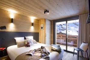 Un dormitorio con una cama y una ventana grande. en Odalys Chalet L'Hermine, en Les Deux Alpes