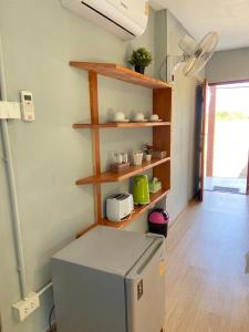 a kitchen with a refrigerator and wooden shelves at ID Garden Home in Ban Cham Kha