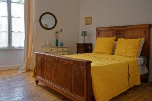 a bedroom with a bed with yellow sheets and a mirror at Gîte entre 2 rives in Montolieu