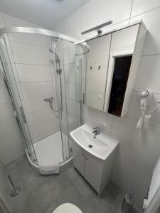 biała łazienka z prysznicem i umywalką w obiekcie Žižkov tower suites w Pradze