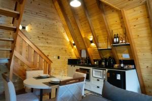 a kitchen with a table in a cabin with wooden walls at Chalé Seiva da Terra in Pinto Bandeira
