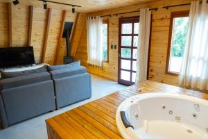 a large living room with a tub and a couch at Chalé Seiva da Terra in Pinto Bandeira