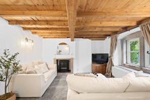 a living room with white furniture and wooden ceilings at Primrose Cottage in Matlock