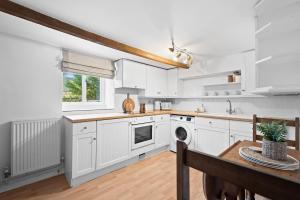 a kitchen with white cabinets and a table at Primrose Cottage in Matlock