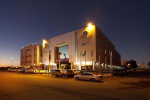 a building with cars parked in a parking lot at night at Intour Qurtoba in Riyadh