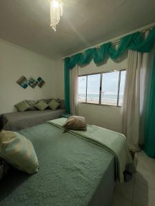 deux lits dans une chambre avec une fenêtre dans l'établissement Mansão pé na areia, à Itanhaém