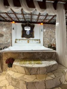 une baignoire dans une pièce avec un mur en pierre dans l'établissement Mansão pé na areia, à Itanhaém