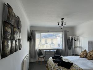 ein Schlafzimmer mit einem Bett und einem Tisch und einem Fenster in der Unterkunft Traeth Rooms in Cardigan