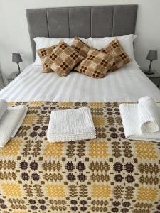 a bed with two towels and pillows on it at Traeth Rooms in Cardigan
