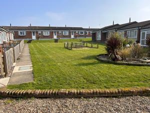 a yard with a grassy yard with houses at Dog Friendly Beachside Cottage Kessingland with private parking in Kessingland