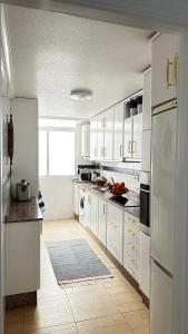 Una cocina con gabinetes blancos y un refrigerador blanco. en Apartament MARA, en Torrevieja