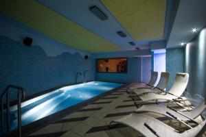 a room with a swimming pool with chairs in it at Hotel Ambrosini in Aprica