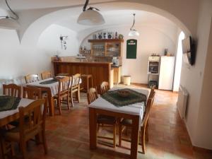 a dining room with tables and chairs and a kitchen at Penzion Bednářův dvůr in Bohušice