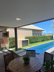 a table with chairs and an umbrella next to a swimming pool at Villa Formentera - Casa 08 by The Coral Beach Resort in Trairi