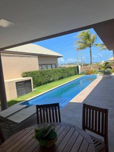 a patio with a table and chairs and a swimming pool at Villa Formentera - Casa 08 by The Coral Beach Resort in Trairi +71 photos
