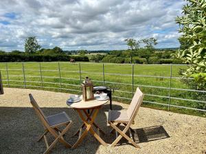 a table with two chairs and a lamp and a field at The Hut at Blackberry Barn in Long Itchington