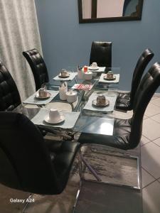 una mesa con sillas negras y platos de comida. en De Serene B&B, en Midrand