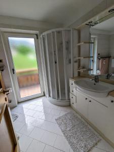 een badkamer met een wastafel en een glazen schuifdeur bij Casa Lagoraiview in Carano