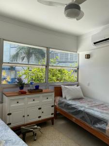 a bedroom with two beds and a dresser and two windows at Anuncio teste in Guarujá +46 photos