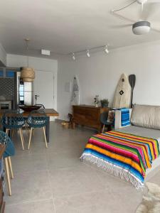 a living room with a bed and a table with a surfboard at Anuncio teste in Guarujá