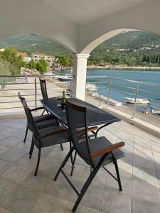 a table and chairs on a balcony with a view of the water at Apartments Štica- Pelješac in Janjina