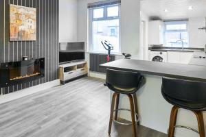 a kitchen with a fireplace and two bar stools at Host & Stay - Thurstane Street in Bolton +4 photos