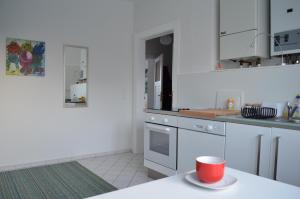 una cocina con armarios blancos y una taza roja en una encimera en F1 - Kunst und Design Dresden, en Dresden