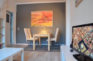ein Wohnzimmer mit einem Tisch, Stühlen und einem Gemälde in der Unterkunft F1 - Kunst und Design Dresden in Dresden