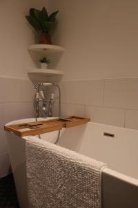 a bathroom with a bath tub with a plant on a shelf at Stunning Walthamstow Village Flat in London